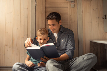 Father and son with book story, smile and bonding, education and learning in home. Reading, parent...