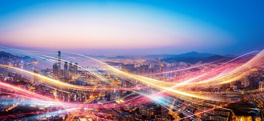 Vibrant streaks of light illuminate a modern cityscape at dusk.
