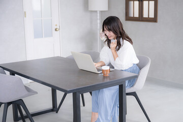 パソコンを見ながら笑顔の若い女性全身