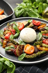 Tasty salad with grilled vegetables and mozzarella cheese on black table, closeup