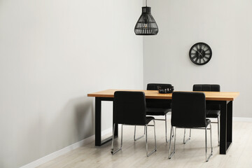 Wooden table with black chairs in stylish dining room