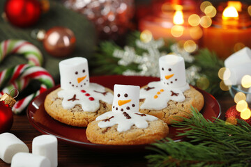 Funny marshmallow snowmen, cookies and festive decor on table, closeup