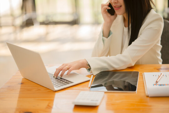 Asian business woman Use a calculator or laptop to make an accounting of income and expenses.  Monthly expenses