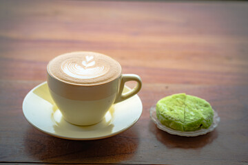 Side view of hot latte coffee with latte art in a white cup on wooden table