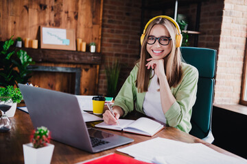 Photo of sweet charming lady assistant wear shirt glasses earphones writing modern gadget indoors...