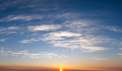 Fototapeta premium Colorful sunset sky with setting sun behind vivid orange and yellow clouds