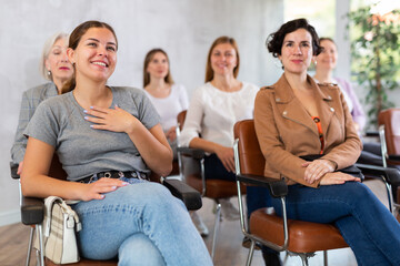 small group of women are sitting in audience and listening to lecture. students of course laugh...