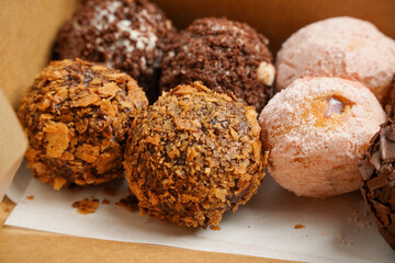 Small, round donuts coated with chocolate.Delicious homemade cookies in paper box on table, close-up