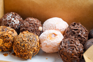 Small, round donuts coated with chocolate.Delicious homemade cookies in paper box on table, close-up