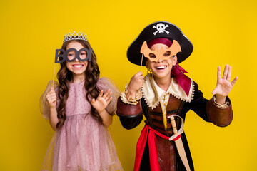 Portrait of two little kids halloween princess pirate costume bat boo glasses isolated on yellow color background