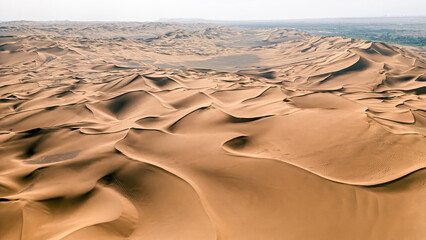 Rolling sand dunes, striped lines in the Kumtag desert, Xinjiang, China, shot from the drone