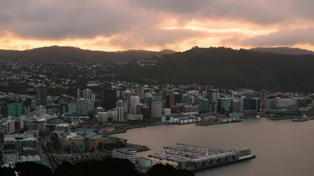 Time lapse of moving clouds over Wellington city at sunset time. Marina ich yachts and waterfront. Aerial wide shot. Mountains range in background. Capital of New Zealand.