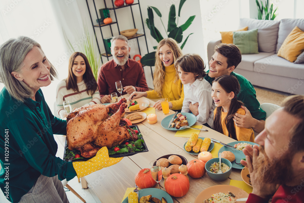 Poster Photo of cheerful people celebrating thanksgiving day family gathering together serving dish stuffed turkey meat