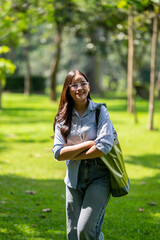 A woman is walking in a park with a green bag