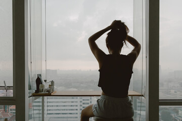 Asian woman relaxed at her windows apartment, enjoy the view and time.