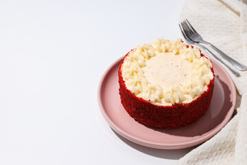 Red velvet cake on pink plate and towel on white background, space for text