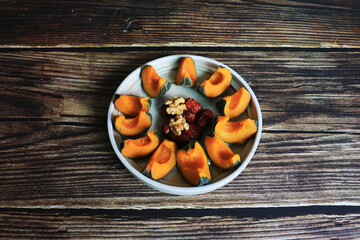 Sliced raw sweet pumpkins, walnuts and dried jujubes in a dish on the wooden table, Korea