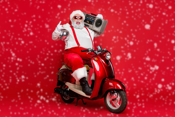 Portrait of his he nice fat cheerful funky Santa hipster wearing cap hat headwear riding motor bike carrying boombox having fun festive isolated on bright vivid shine vibrant red color background