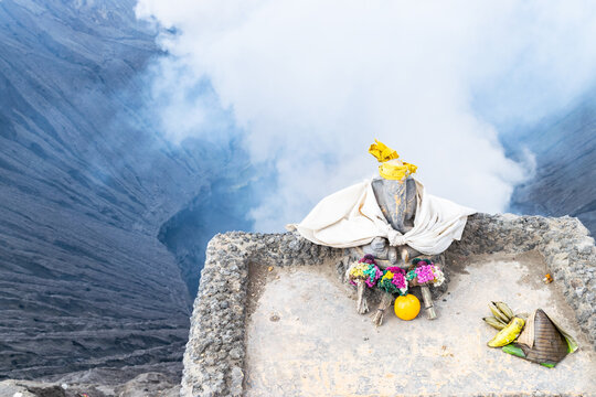 Stone statue of ganesha with offerings overlooking the smoking crater of mount bromo volcano in java
