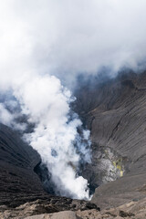 White smoke rising from the crater of an active volcano on a cloudy day