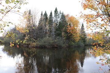 Autumn background with colorful trees and calm water. Canada and Quebec landscape in october. Autumn calendar and the St-Charles river in Quebec. The reflection of the water and the fall season. 