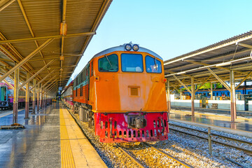 Yellow locomotive diesel train start departure passing near the passenger station in the city.