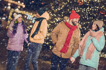 Portrait of group positive satisfied partners hold arms walking chatting conversation garland lights outside