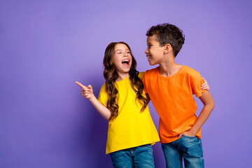 Photo of charming two little children laughing point empty space wear trendy orange yellow outfit isolated on violet color background