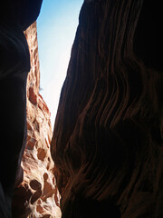 Looking up to the sky and narrow red rock sandstone walls of Buckskin Gulch slot canyon