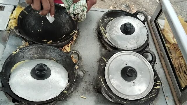 View of the skilled hands of a street "leker cake" seller who makes leker cakes using 4 pans that are opened and closed alternately so that the leker cakes cook evenly and perfectly.