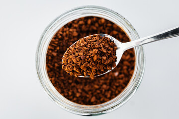 pantry staple close-up, spoonful of instant coffee over clear glass jar shot from above