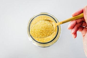 pantry staple close-up, spoonful of cous cous over clear glass jar shot from above