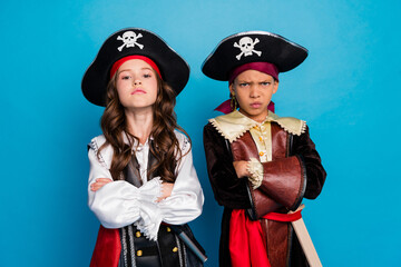 Photo of two serious small kids halloween pirate costume crossed arms isolated on blue color...