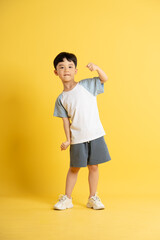 Full body image of asian kid boy wearing summer clothes posing on yellow background