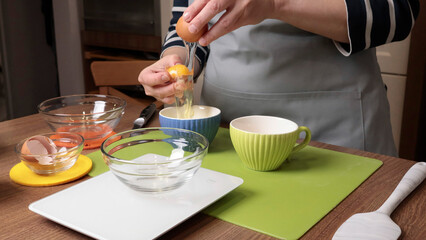 Process of making dough. Woman separates egg white from yolk in kitchen. Scales and eggs, utensils...