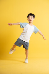 Full body image of asian kid boy wearing summer clothes posing on yellow background