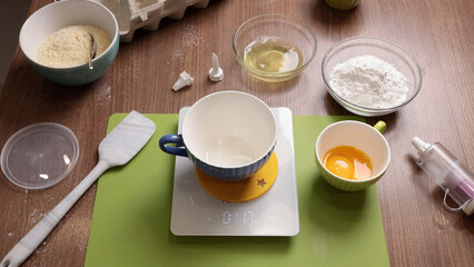 Process of weighing products for making dough. Scales, dishes on wooden table close-up at home. View from above.