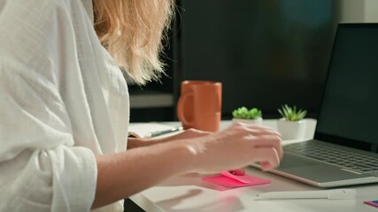 Woman is using sticky notes on her laptop screen to organize her work while working remotely from home. Concept of planning and task management in office work