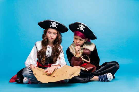 Full size photo of two small kids halloween pirate costume treasure map isolated on blue color background