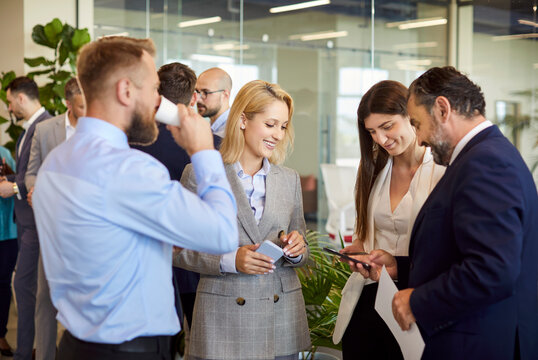 A group of business people talking in the hall and laughing, close-up. Young businessmen exchange contacts. Concept of business acquaintance, meeting in the lobby of a conference room