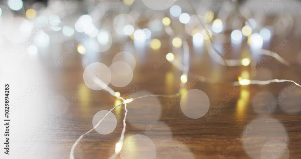 Poster bokeh lights animation over blurred string lights on wooden surface
