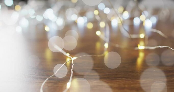 Bokeh lights animation over blurred string lights on wooden surface