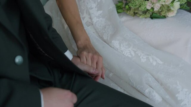 A touching moment as the bride and groom hold hands during their wedding ceremony, symbolizing their love and commitment to one another.
