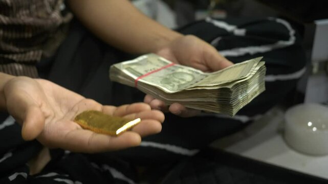 Hands comparing 24k raw gold and Indian rupee banknotes for gold investment, Closeup