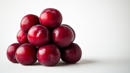 A pyramid of fresh red plums on a white background with natural lighting