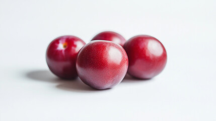 Fresh red plums arranged on a white surface in natural light during the afternoon