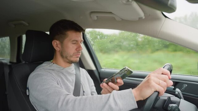 Driver using smartphone while driving car, distracted by messages on his phone. Dangerous driving of a vehicle, violation of traffic rules