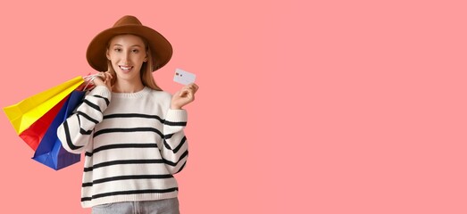Beautiful happy young woman holding credit card and shopping bags on pink background with space for text