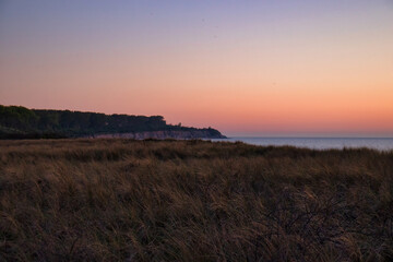 Colorful sky over grass and cliffs at a beach at the Baltic Sea on a spring night.