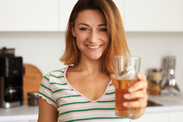 Young woman with glass of juice in kitchen, closeup